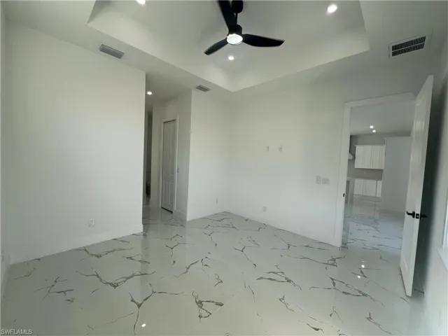Empty room featuring a tray ceiling and ceiling fan