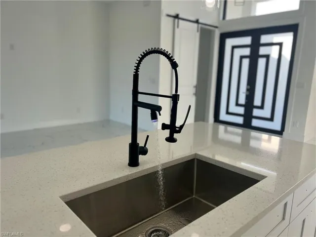 Details featuring white cabinetry, a barn door, light stone counters, and sink