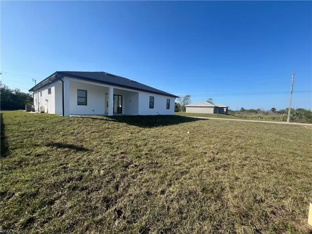 Back of property featuring a yard and cooling unit