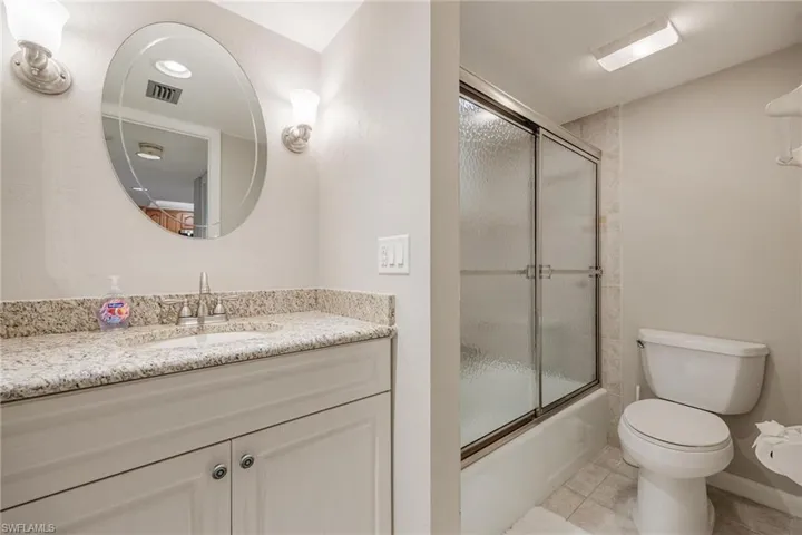 Full bathroom featuring tile flooring, combined bath / shower with glass door, vanity, and toilet