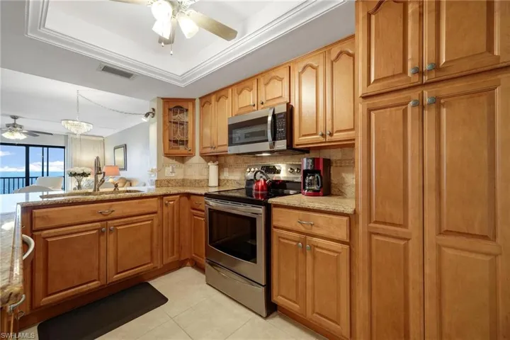 Kitchen featuring stainless steel appliances, ceiling fan, light stone countertops, and tasteful backsplash