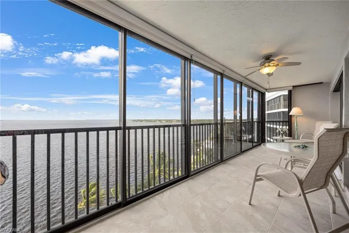 sunroom featuring a wealth of natural light, ceiling fan, and a water view