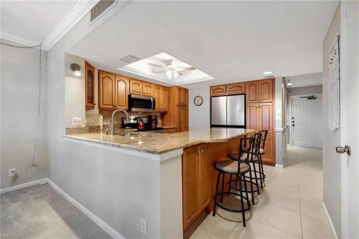 Kitchen with appliances with stainless steel finishes, kitchen peninsula, tasteful backsplash, ceiling fan, and a kitchen bar