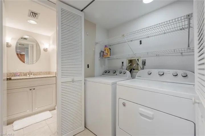 Washroom with washer and dryer, washer hookup, hookup for an electric dryer, sink, and light tile floors