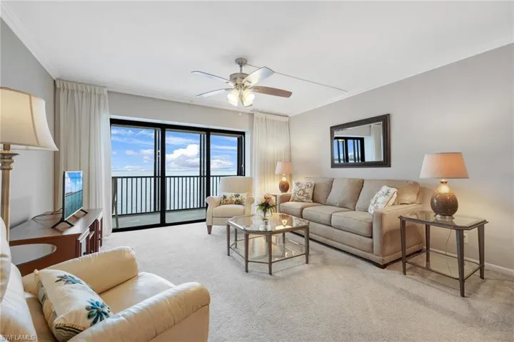 Carpeted living room with crown molding and ceiling fan
