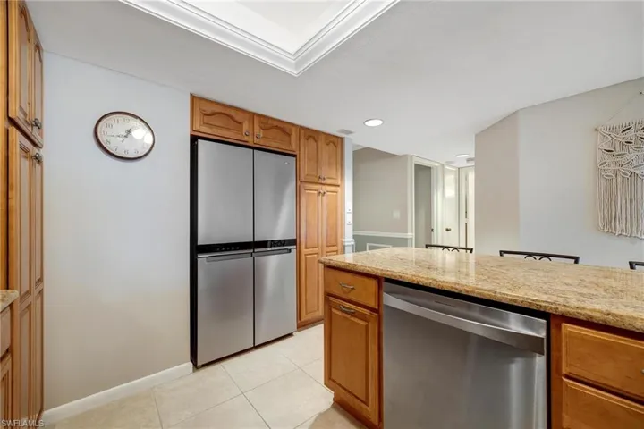 Kitchen featuring light tile floors, light stone counters, and stainless steel appliances
