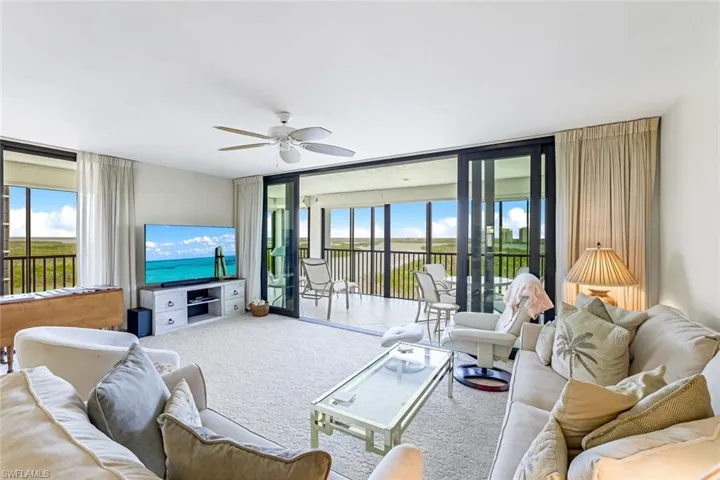 Living room featuring expansive windows, carpet flooring, and a ceiling fan