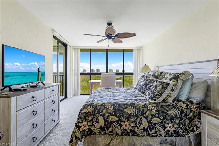 Bedroom with expansive windows, light colored carpet, access to outside, a ceiling fan, and a textured wall