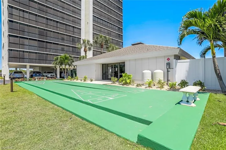 View of property's community with shuffleboard and a lawn
