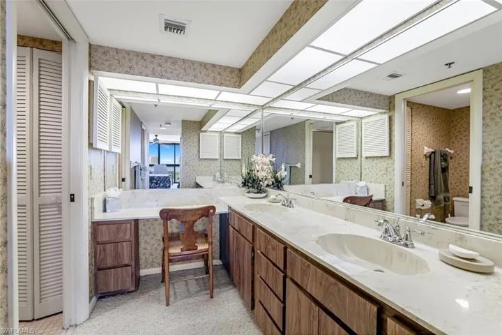 Bathroom with wallpapered walls, a closet, and double vanity