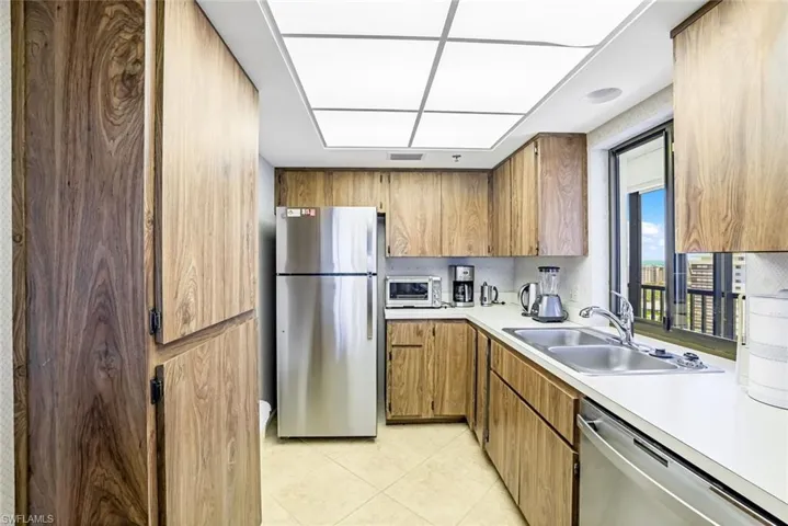 Kitchen featuring brown cabinets, appliances with stainless steel finishes, light countertops, and light tile patterned floors