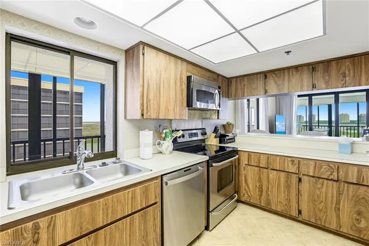 Kitchen featuring appliances with stainless steel finishes, light countertops, brown cabinetry, and light tile patterned floors