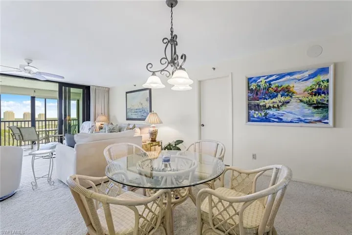Carpeted dining room with floor to ceiling windows and a ceiling fan