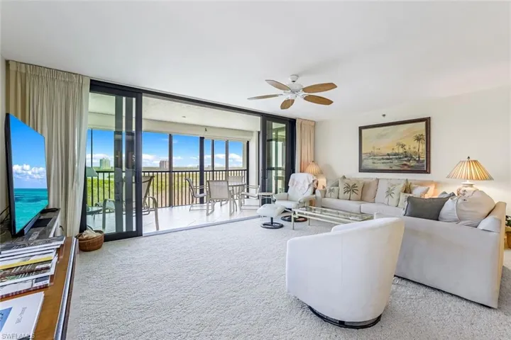Carpeted living room featuring floor to ceiling windows and ceiling fan