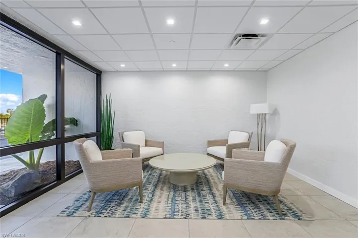 Living area featuring a textured wall, a wall of windows, recessed lighting, a paneled ceiling, and light tile patterned floors