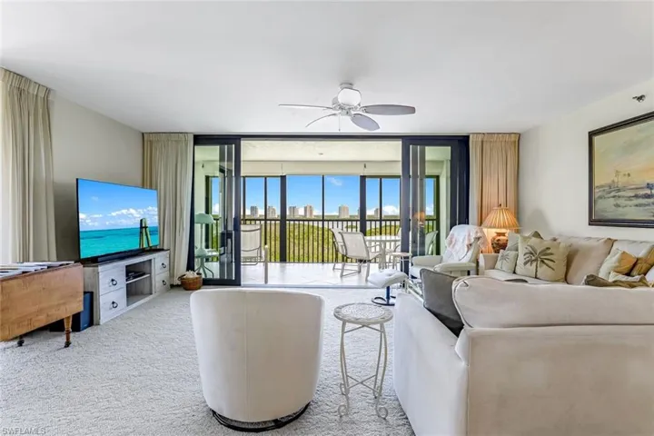 Living room featuring floor to ceiling windows, carpet flooring, and ceiling fan
