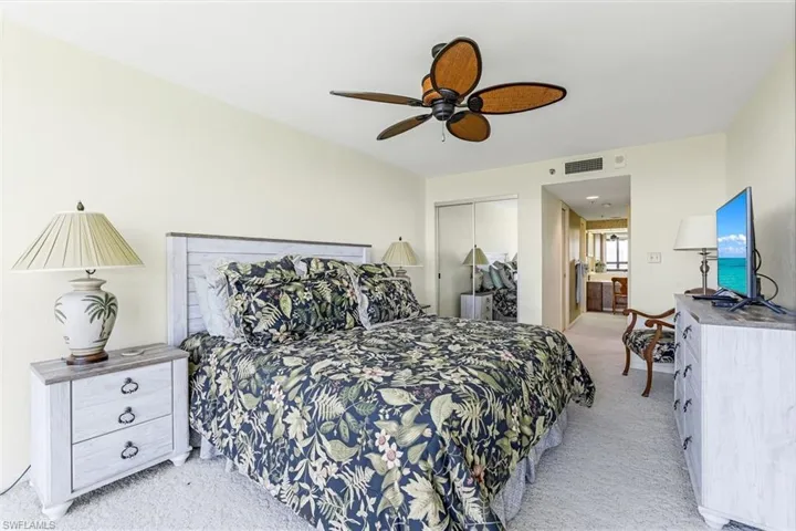 Bedroom with light carpet, a closet, ensuite bath, and ceiling fan