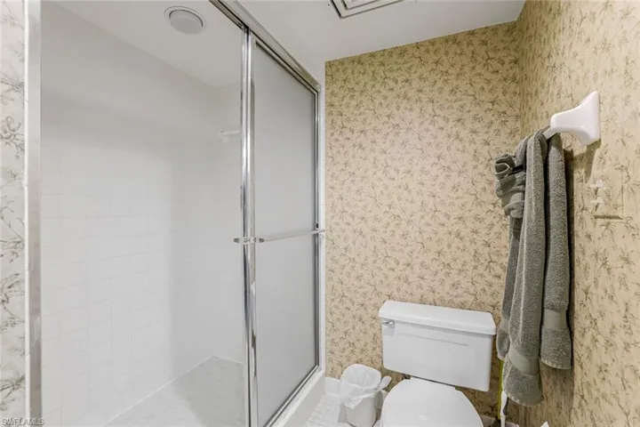Bathroom featuring wallpapered walls and a stall shower