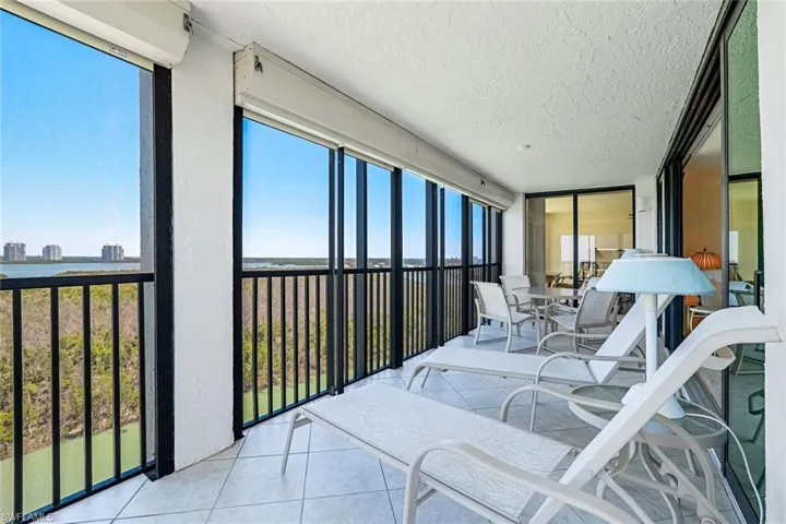 Sunroom / solarium with a wall of windows, tile patterned floors, a water view, and a textured ceiling