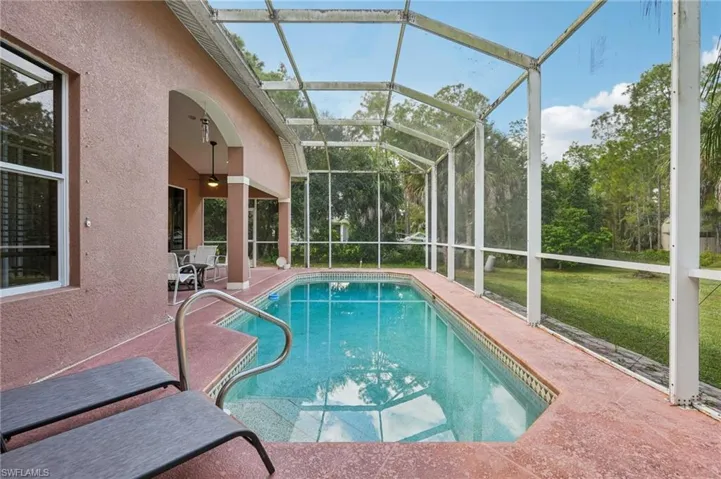 Swimming pool featuring a sunroom, a patio area, a lanai, a yard, and ceiling fan