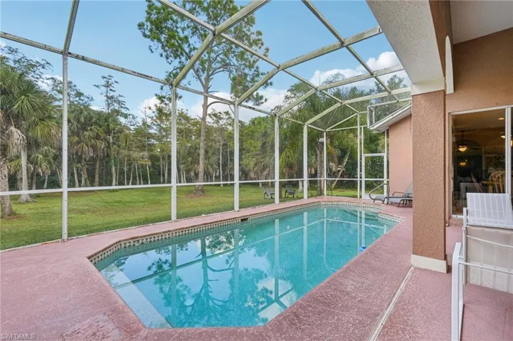 Swimming pool with a sunroom, a patio area, a lanai, and a yard