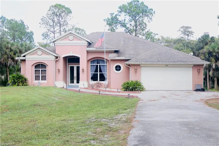 View of front of house with french doors, driveway, stucco siding, a front lawn, and a garage
