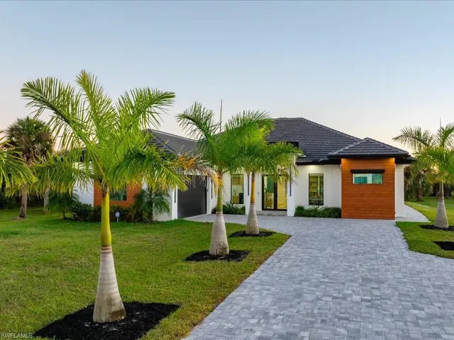 View of front facade featuring decorative driveway, a front yard, a tile roof, and stucco siding