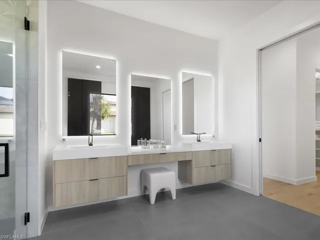 Bathroom with double vanity, a walk in closet, and a stall shower