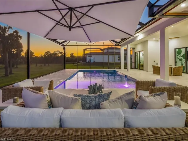 Pool at dusk with outdoor lounge area, an outdoor pool, glass enclosure, and a patio area