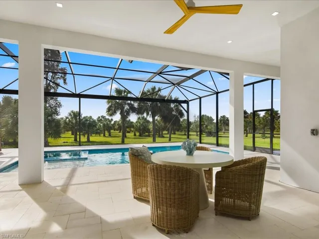 View of swimming pool with a patio area, a sunroom, glass enclosure, a lawn, and a pool with connected hot tub