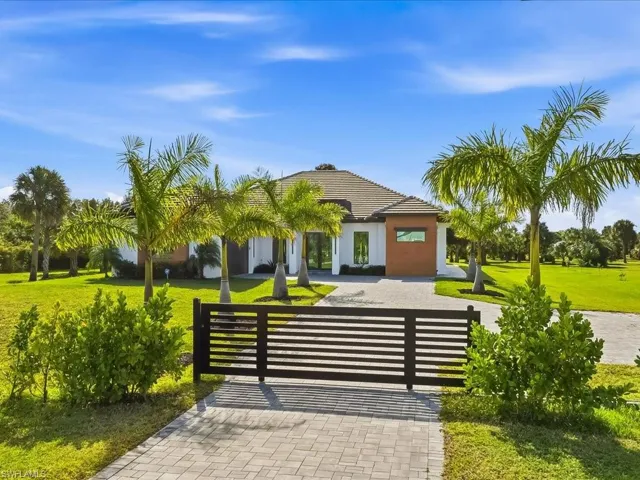 View of front of home with a front yard, decorative driveway, and a gate