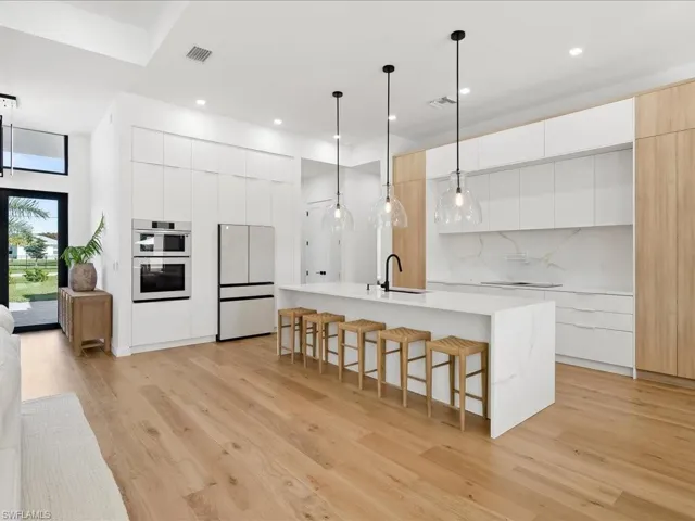 Kitchen with white cabinets, modern cabinets, hanging light fixtures, a breakfast bar area, and freestanding refrigerator