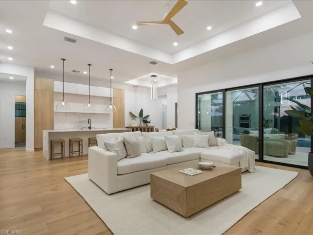 Living area with a tray ceiling, light wood-style flooring, recessed lighting, and a ceiling fan
