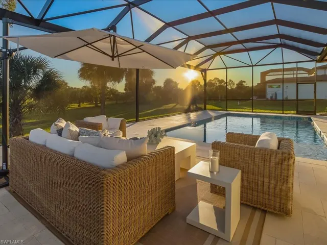 Pool at dusk with glass enclosure, an outdoor pool, an outdoor hangout area, and a patio area