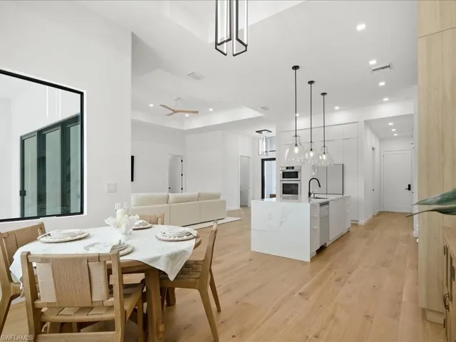 Dining space with a tray ceiling, light wood-style floors, recessed lighting, and a ceiling fan