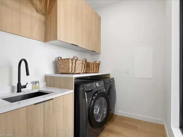 Laundry room featuring cabinet space, washer and dryer, and light wood-style floors