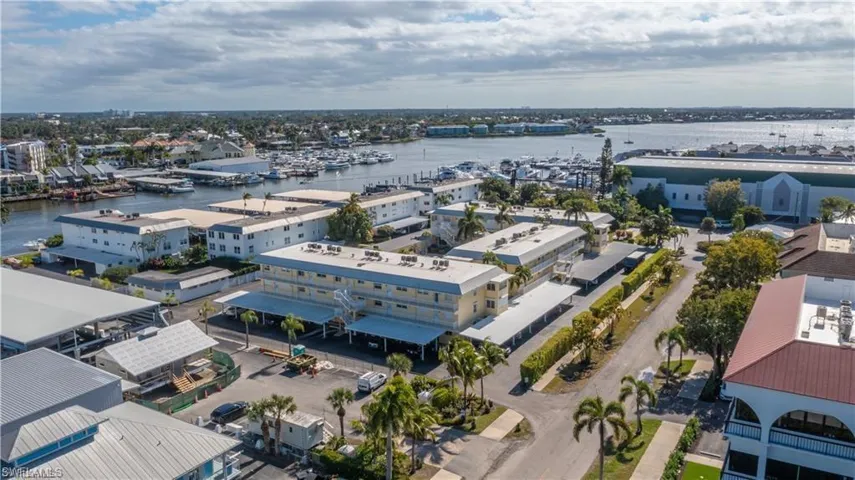 Waterfront complex featuring covered parking, mature landscaping, and marina access