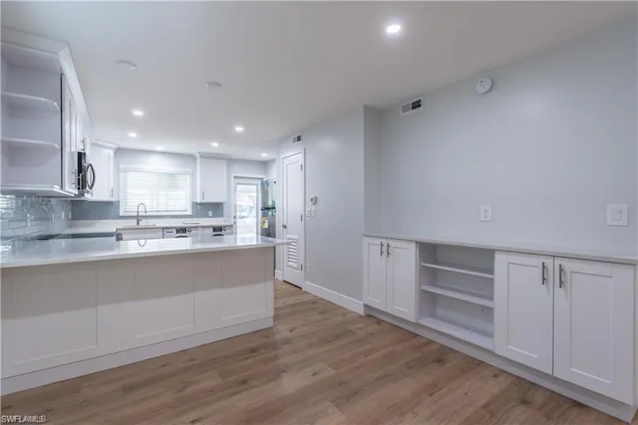 Contemporary kitchen with white cabinetry, light-toned countertops, and a full tile backsplash
