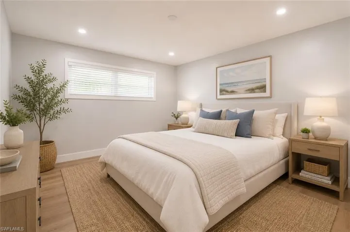 Recessed lighting illuminating a spacious room with wood-finish flooring, a wide window with blinds, and light-toned walls