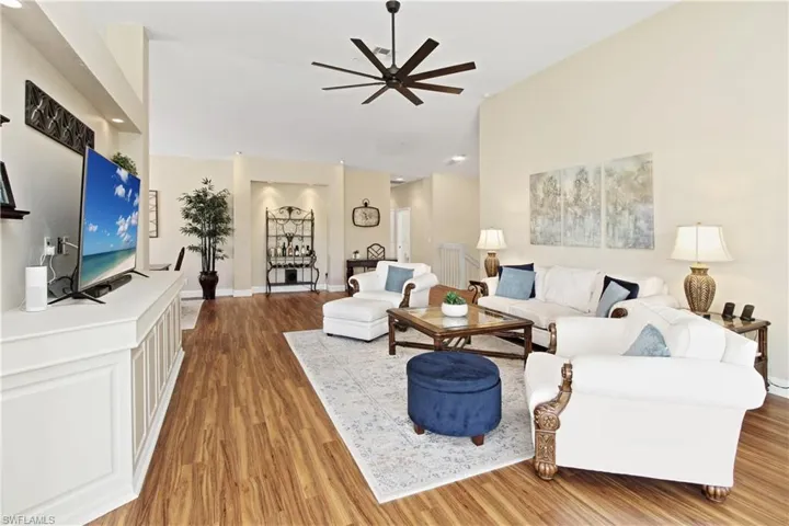 Living area with a ceiling fan, light wood-type flooring, and a high ceiling