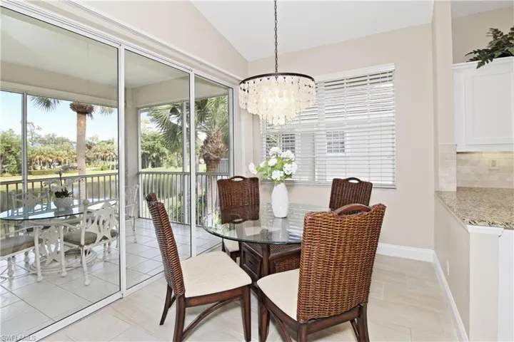 Dining room with hanging lights, healthy amount of natural light, vaulted ceiling, and light tile patterned flooring