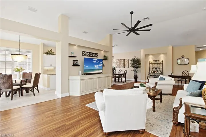 Living area featuring light wood finished floors, a ceiling fan, and a high ceiling