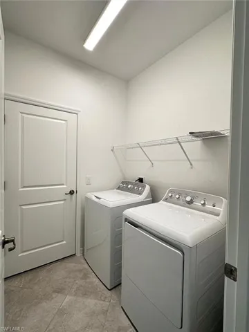 Laundry area featuring separate washer and dryer and light tile patterned flooring