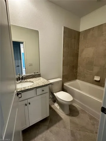 Bathroom featuring a textured wall, vanity, and shower / bath combination
