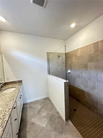 Bathroom with walk in shower, vanity, recessed lighting, and light tile patterned floors