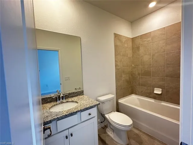 Bathroom featuring vanity,  shower combination, and a textured wall