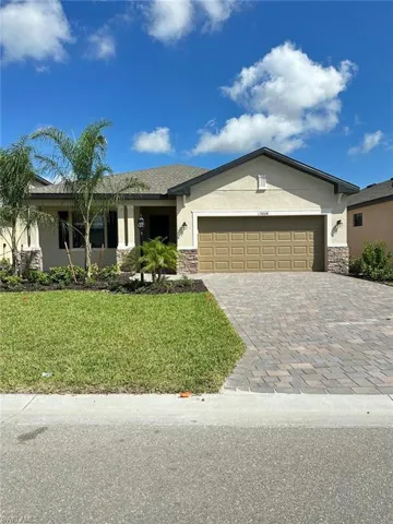 Ranch-style home with stone siding, stucco siding, and decorative driveway