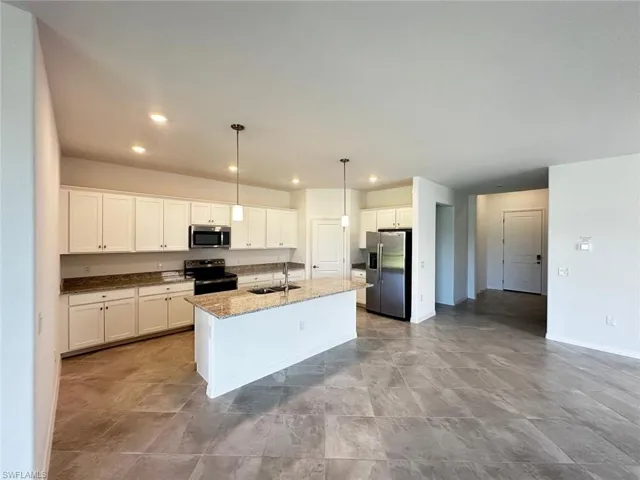 Kitchen with dark stone countertops, stainless steel appliances, white cabinets, pendant lighting, and recessed lighting
