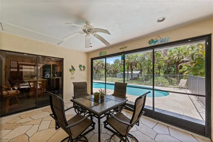 Screened lanai featuring flagstone-style flooring, a ceiling fan, and direct access to the outdoor pool area