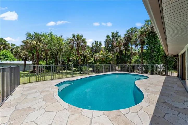 Freeform swimming pool with integrated steps, surrounded by flagstone-style patio pavers